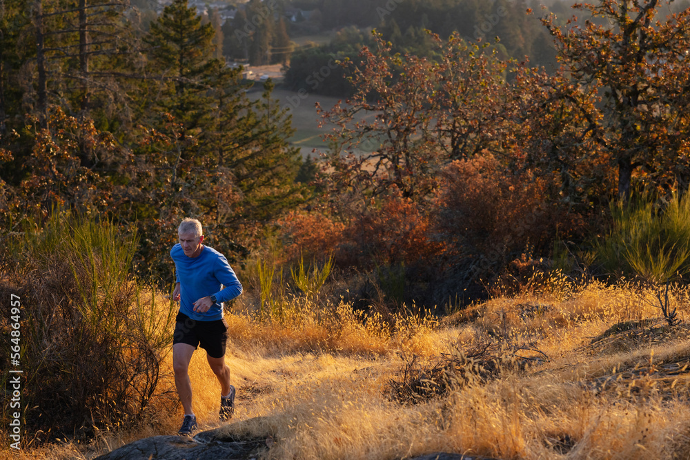 Man running uphill on trail to mountain sunrise. to mountain sun Man running uphill on trail to mountain sunrise. to mountain sun