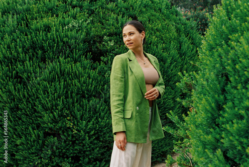 Woman in green clothes posing against green bushes photo