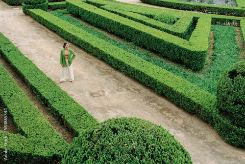 Woman in green standing still on a garden path