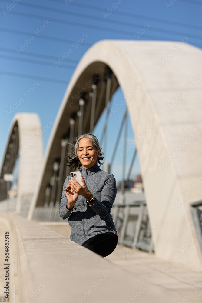 Woman Uses Cell Phone While Exercising On A Bridge Woman Uses Cell Phone While Exercising On A Bridge
