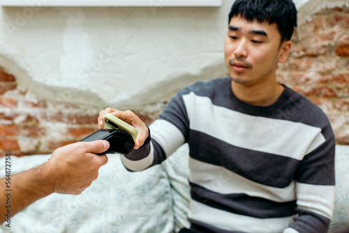 Man in cafe paying the check with mobile phone photo