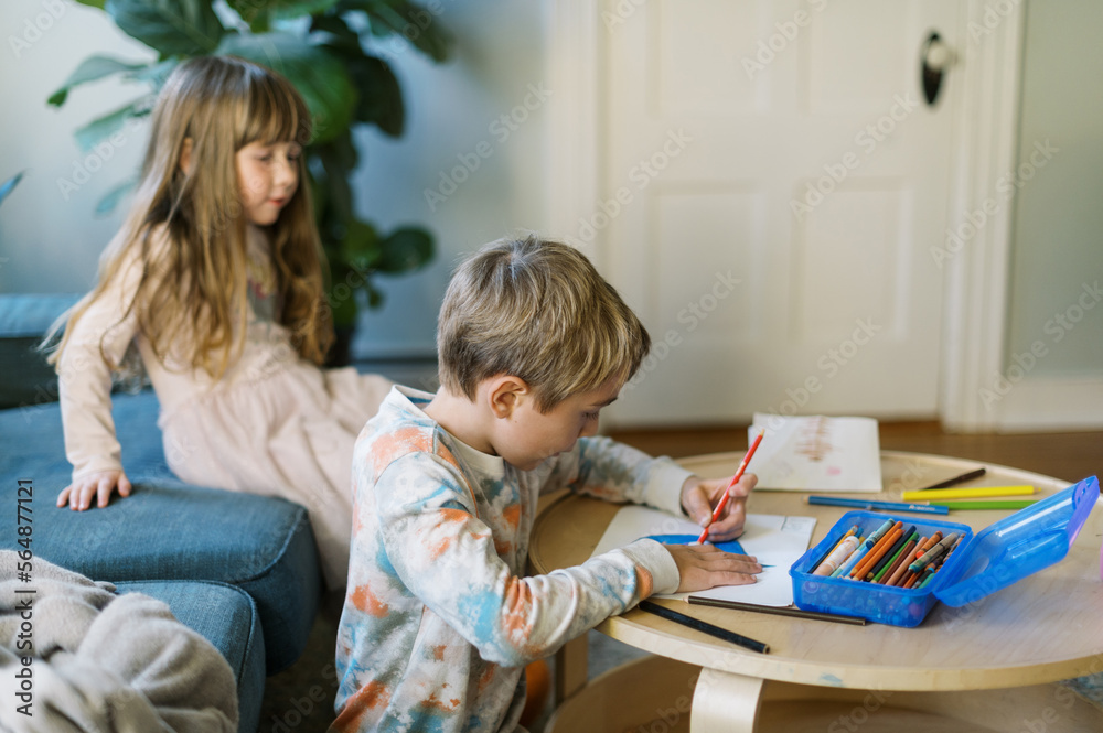 Brother and sister coloring at a table at home Brother and sister coloring at a table at home