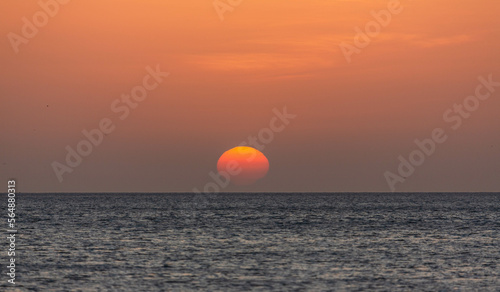 Fototapeta Naklejka Na Ścianę i Meble -  Sunrise with sun and orange sky, blue water of sea. Wallpaper