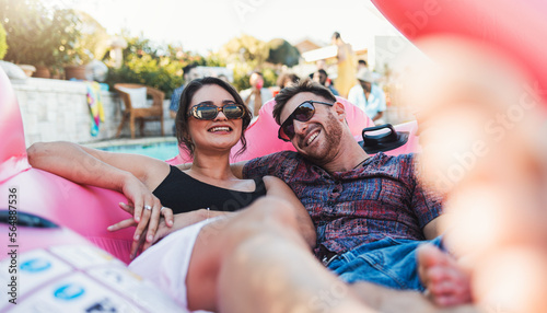 Fotografie Couple, relax and smile for pool party on inflatable floating in the water enjoying summer vacation together
