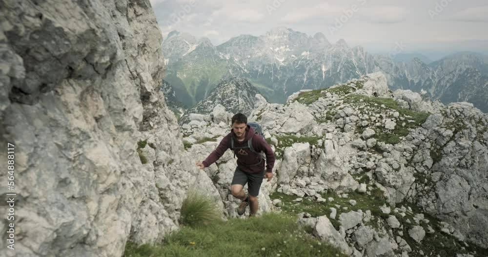 Camera tracking hiker in front on a grenn grassy path towards the top of mountain. Beautiful moutains in the back. Camera tracking hiker in front on a grenn grassy path towards the top of mountain. Beautiful moutains in the back.