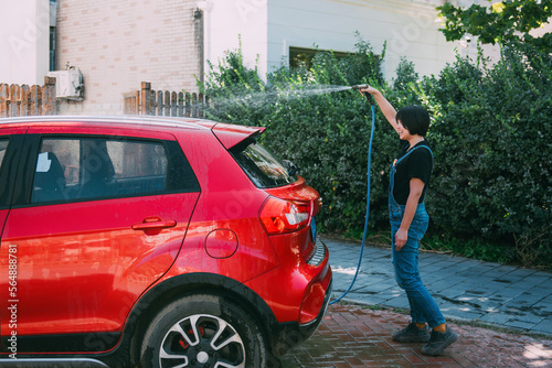 Young woman washing a red car