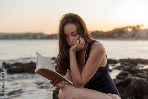 Woman reading a book by the sea photo