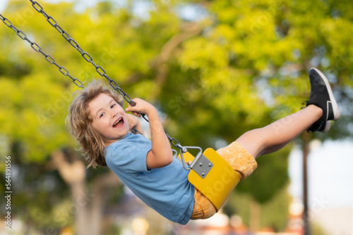 Outdoor playground. Funny kid on swing. Little boy swinging on playground. Happy cute excited child on swing. Cute child swinging on a swing. Crazy playful child swinging very high.