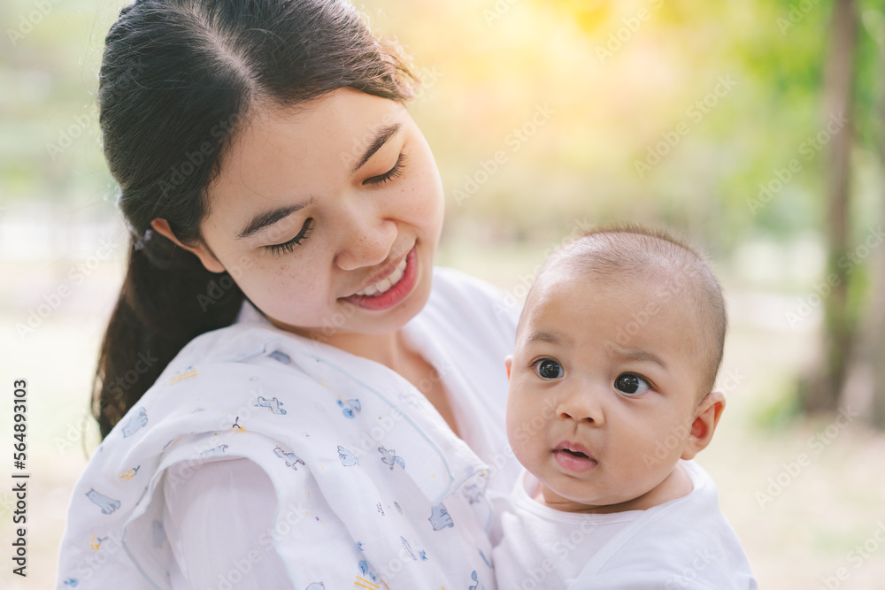Asian mothers or single moms are smiling and hugging newborn babies. Family doing activities and relaxing in the park. Concepts about the duties of a wife and mother in raising children and family. Asian mothers or single moms are smiling and hugging newborn babies. Family doing activities and relaxing in the park. Concepts about the duties of a wife and mother in raising children and family.