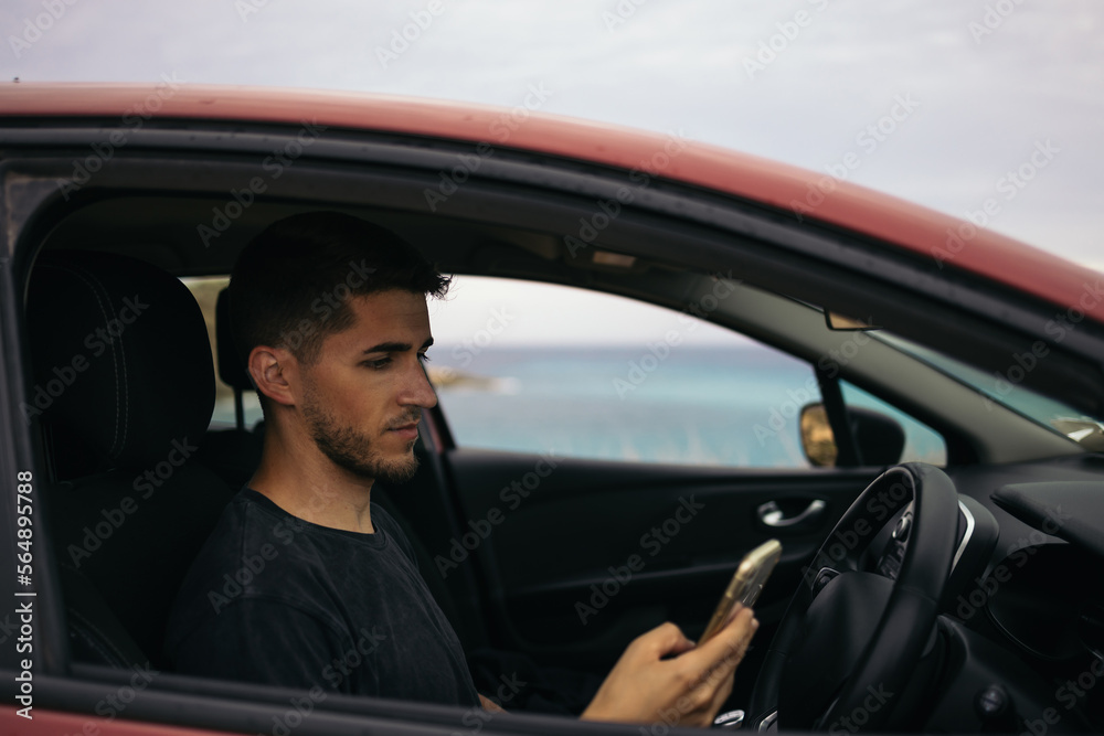 Man using the mobile in the car parked in front of the sea Man using the mobile in the car parked in front of the sea
