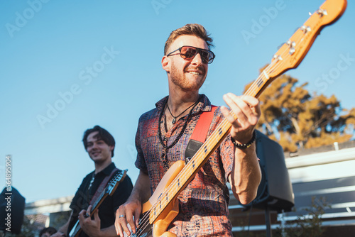 Guitar, music and party with a band outdoor at a celebration playing a song as a musician or artist. Happy, fun and performance with a man guitarist holding an instrument to perform at a birthday