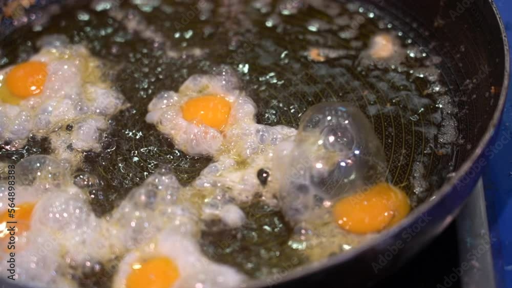 closeup of a man frying small quail eggs in a pan with plenty of oil closeup of a man frying small quail eggs in a pan with plenty of oil