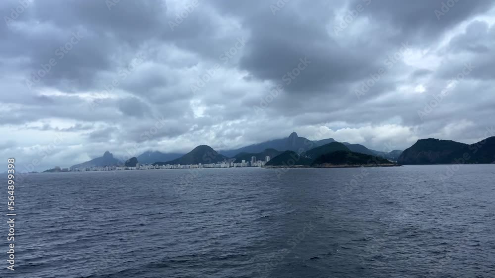 View from the ocean on the coast of the Brazilian city of Rio de Janeiro. A beautiful calm ocean going into the distance to land. Cloudy sky. Calm water. View from the ocean on the coast of the Brazilian city of Rio de Janeiro. A beautiful calm ocean going into the distance to land. Cloudy sky. Calm water.