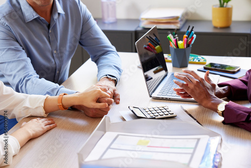 Crop couple holding hands during mortgage appointment