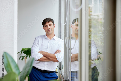 Positive formal male standing near window photo