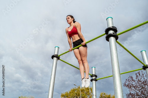 Fit sportswoman doing muscle up exercise on high bar photo