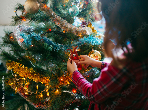 Kid  hanging ornament in Christmas tree in daylight