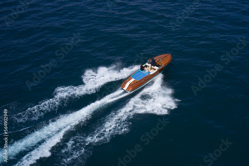 Luxurious wooden boat fast movement on dark water. Classic Italian wooden boat fast moving aerial view. Top view of a wooden powerful motor boat.