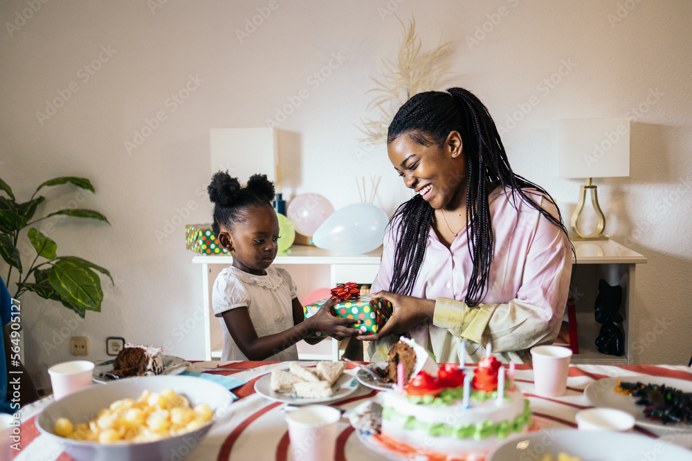 Little black girl giving her older sister a present on her birthday Little black girl giving her older sister a present on her birthday