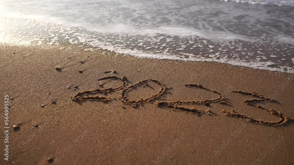 2023 figures on sandy beach Happy New Year 2023, number hand written in the golden sand on beautiful sunset golden light. The sea wave washes away the inscription 2023 on the yellow sand close-up. 2023 figures on sandy beach Happy New Year 2023, number hand written in the golden sand on beautiful sunset golden light. The sea wave washes away the inscription 2023 on the yellow sand close-up.