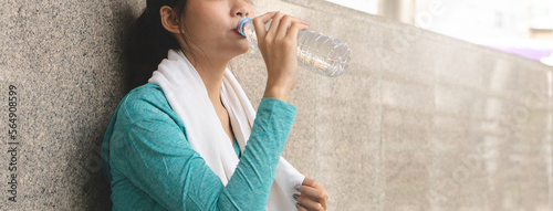 Obraz na płótnie Asian sporty woman drinking water to rehydrate after jogging exercise