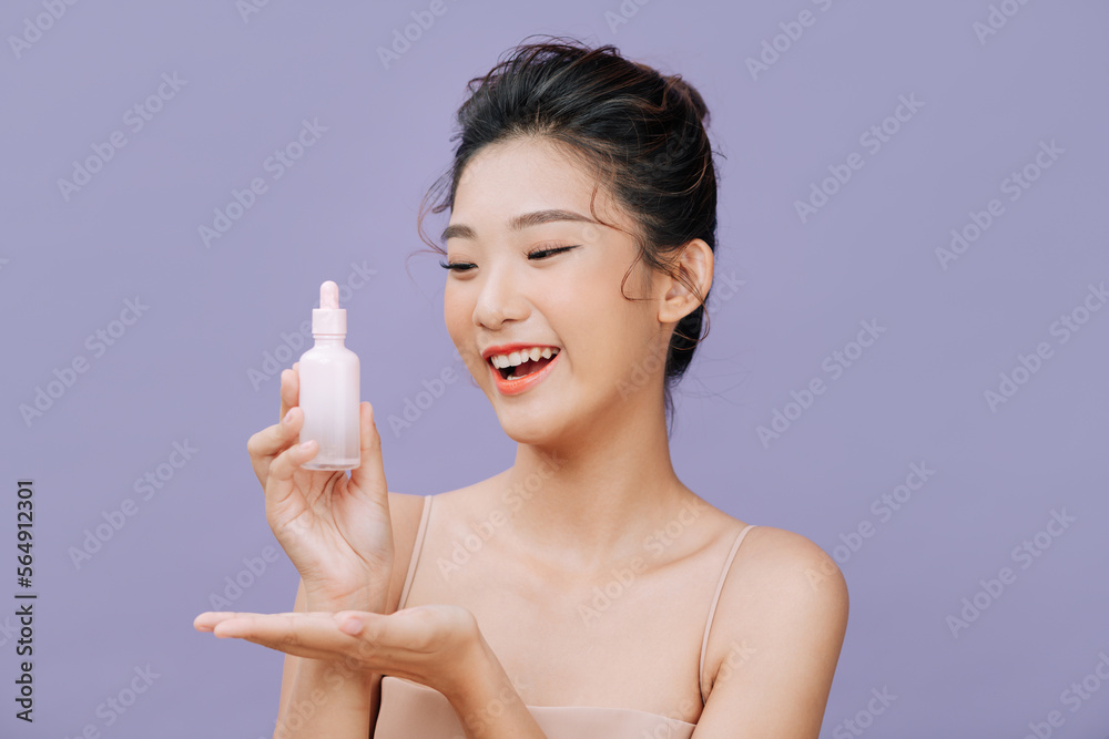 © Marc Tran/Stocksy - Image of nice half-naked woman holding serum bottle over purple © Marc Tran/Stocksy - Image of nice half-naked woman holding serum bottle over purple