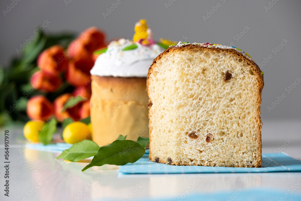 Traditional Easter cake with white icing and spring decoration, orange tulips on background. Happy Easter. Recipe of Easter bakery. Festive pastry for spring holidays.