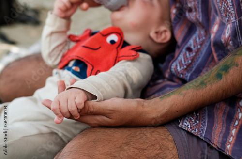 father giving bottle to son  photo