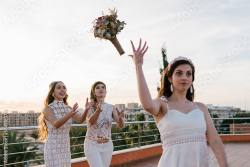 Bride throwing bouquet to bridesmaids photo