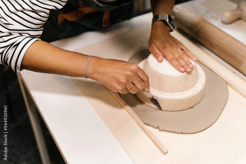 Crop artisan cutting clay piece while creating pot Crop artisan cutting clay piece while creating pot