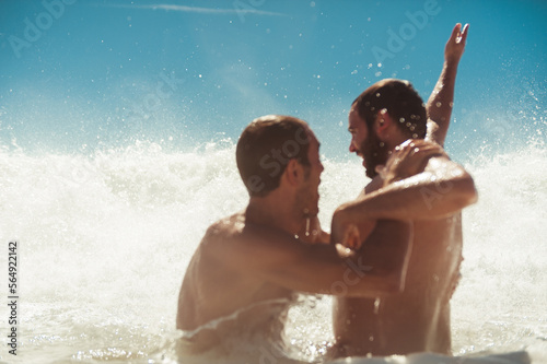 Joyful friends having fun playing with sea waves photo