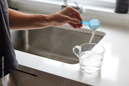 Woman pouring powder supplement in the glass photo