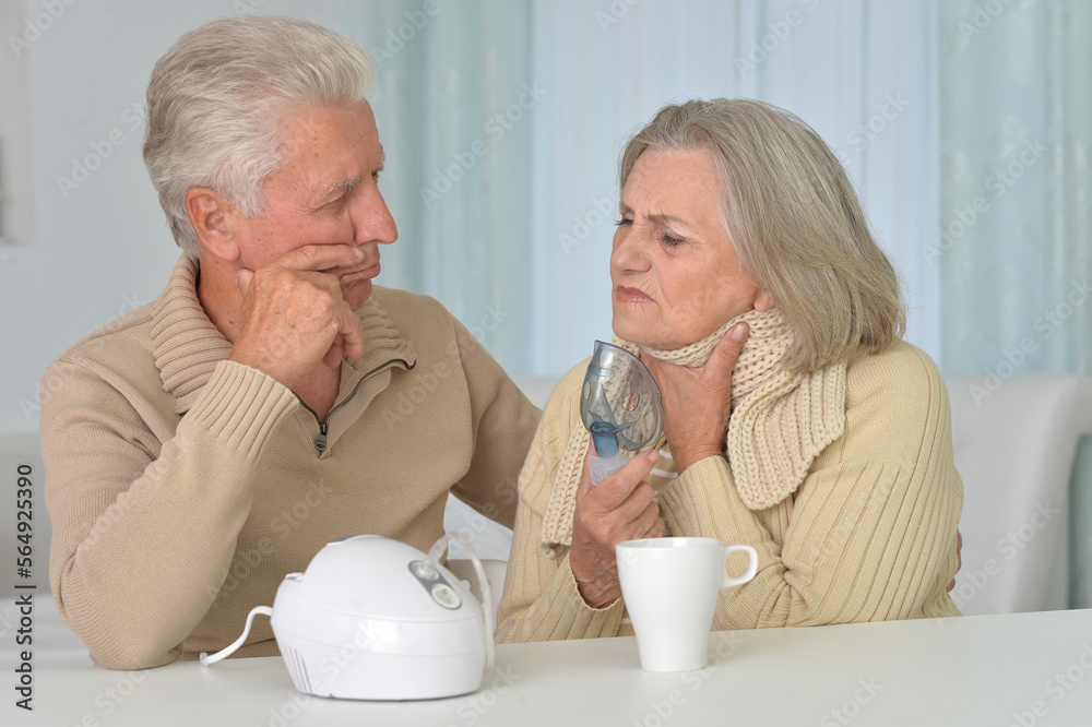 Sick senior woman with inhaler and man at home Sick senior woman with inhaler and man at home