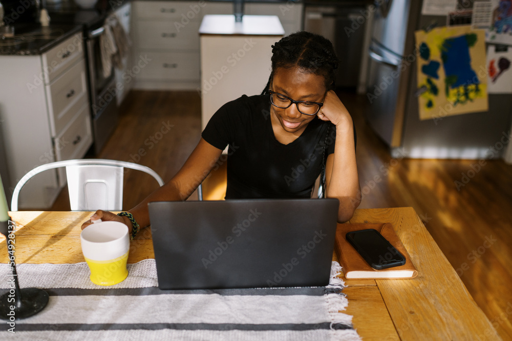 smiling black teenage girl working at her laptop in her home smiling black teenage girl working at her laptop in her home