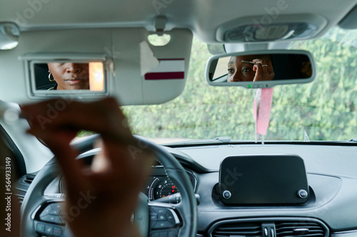 Woman applying makeup in a car mirror photo