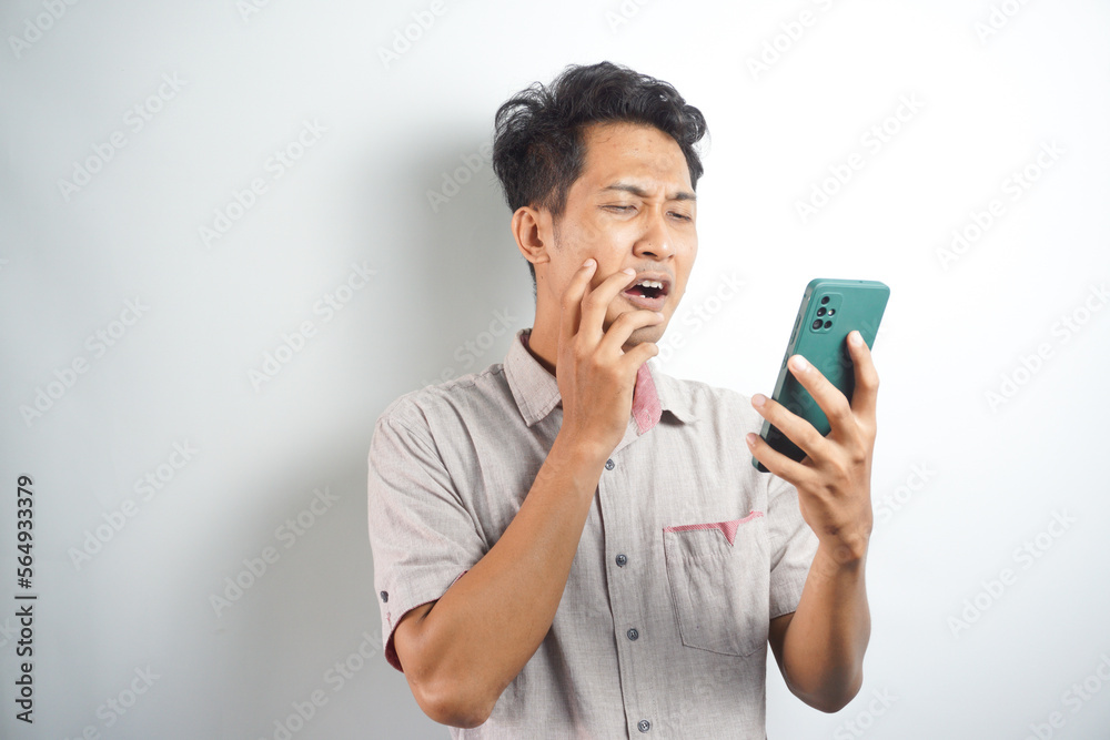 sad handsome asian man looking at notification on his cellphone sad handsome asian man looking at notification on his cellphone