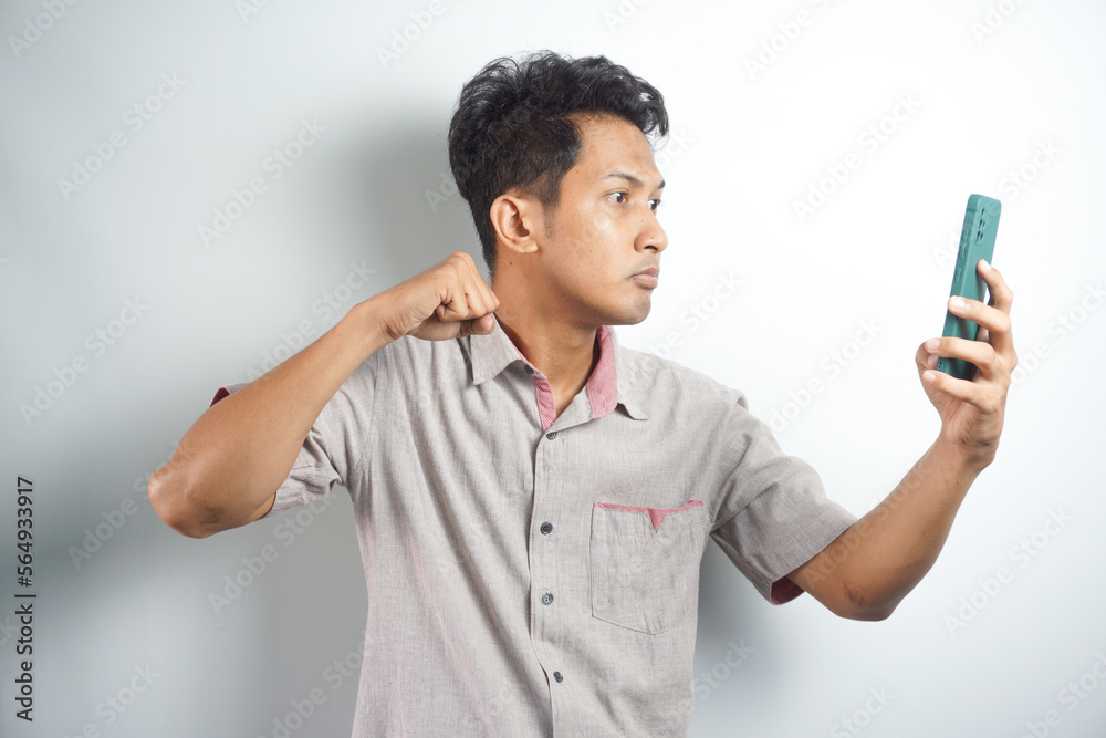 Young asian man angry, frustrated and furious with his phone, angry with customer service over white background. Young asian man angry, frustrated and furious with his phone, angry with customer service over white background.