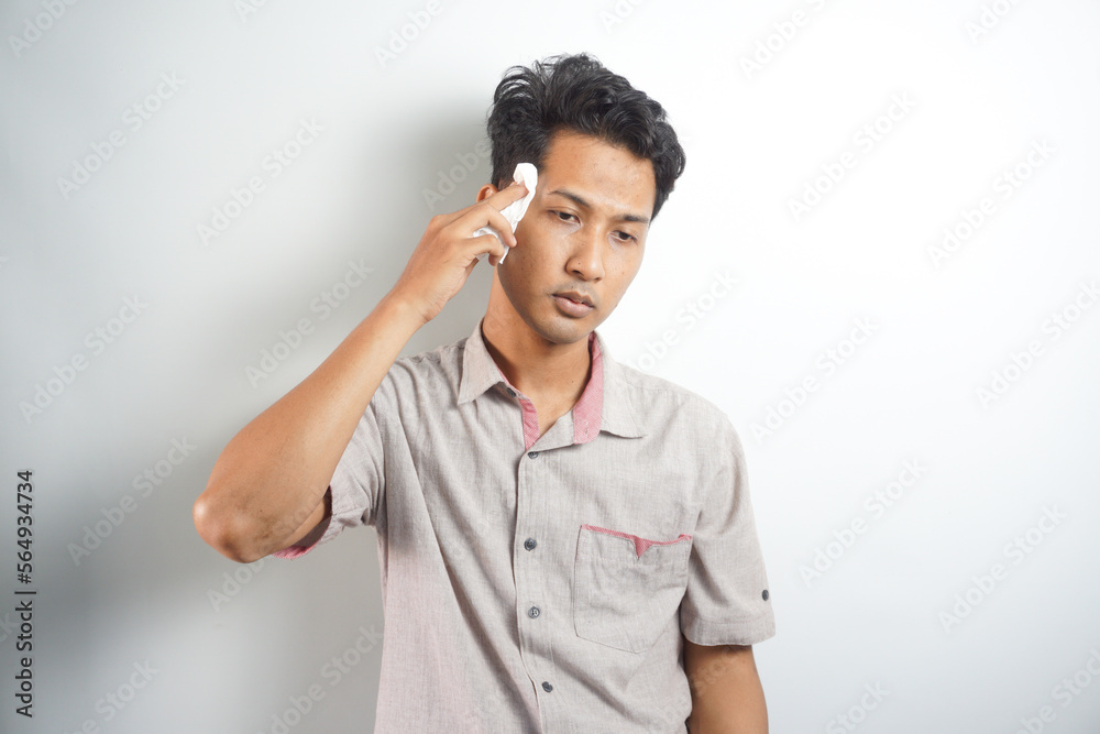 Isolated on white studio background overheated sweaty young man suffering from heat stroke or high temperature, using paper napkin. Head shot close up portrait tired millennial guy feeling unhealthy. Isolated on white studio background overheated sweaty young man suffering from heat stroke or high temperature, using paper napkin. Head shot close up portrait tired millennial guy feeling unhealthy.