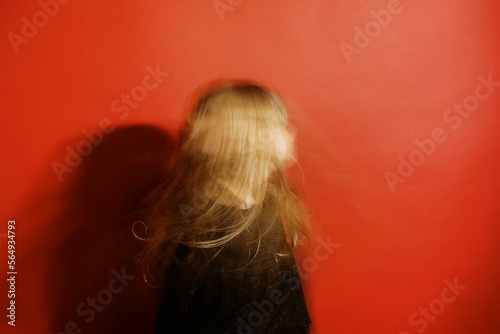 blurry portrait of girl in front of red wall photo