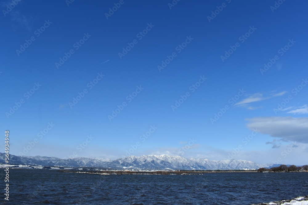 雪が積もった琵琶湖畔と比良山