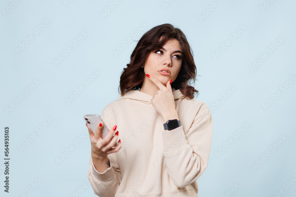 Thinking girl teen looking up, beautiful young woman thinking and looking upwards with smartphone