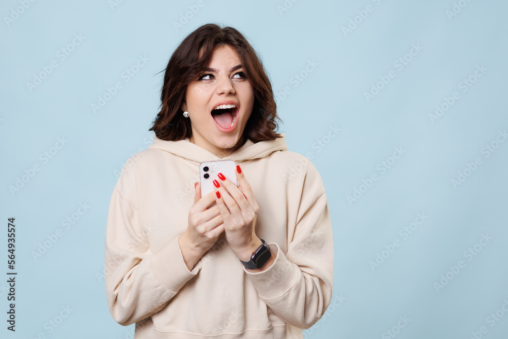 A pretty teenager in a studio shot, laughing and looking at camera joyful as she shops, smartphone. A pretty teenager in a studio shot, laughing and looking at camera joyful as she shops, smartphone.
