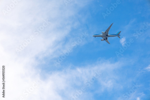 View of airplane flying in blue sky among white clouds. . High quality photo