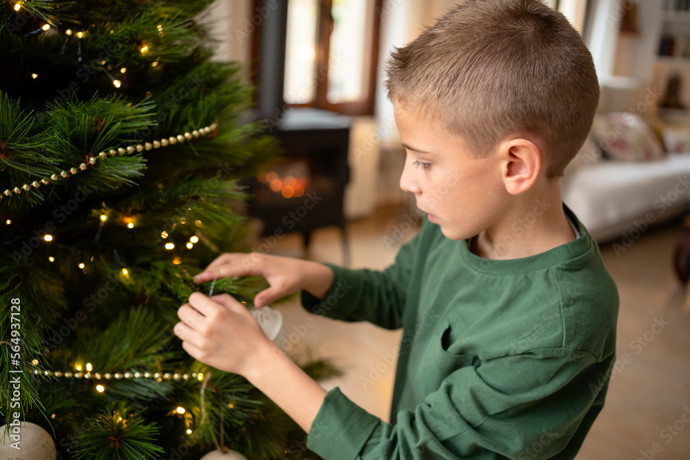 © Albert Martinez/Stocksy - Boy decorating Christmas tree © Albert Martinez/Stocksy - Boy decorating Christmas tree