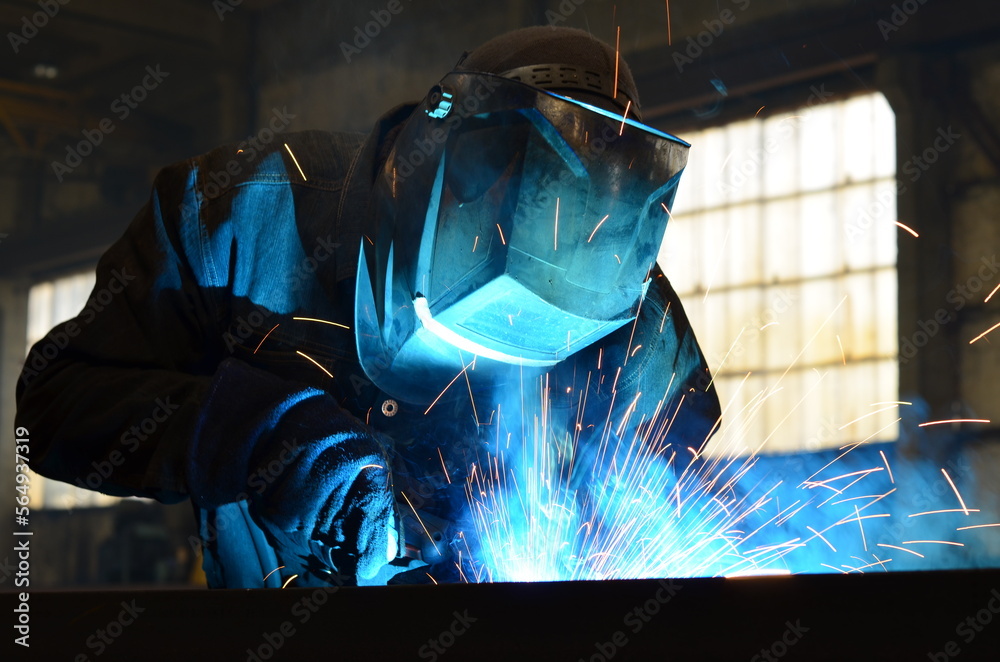 Workers wearing industrial uniforms and Welded Iron Mask at Steel welding plants, industrial safety first Workers wearing industrial uniforms and Welded Iron Mask at Steel welding plants, industrial safety first