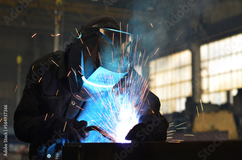Workers wearing industrial uniforms and Welded Iron Mask at Steel welding plants, industrial safety first	