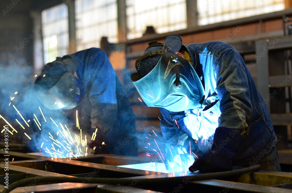 Workers wearing industrial uniforms and Welded Iron Mask at Steel welding plants, industrial safety first Workers wearing industrial uniforms and Welded Iron Mask at Steel welding plants, industrial safety first