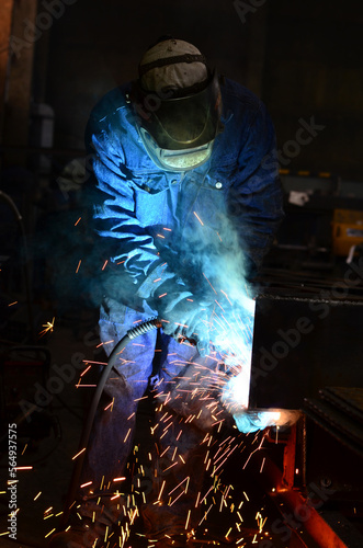 Workers wearing industrial uniforms and Welded Iron Mask at Steel welding plants, industrial safety first 