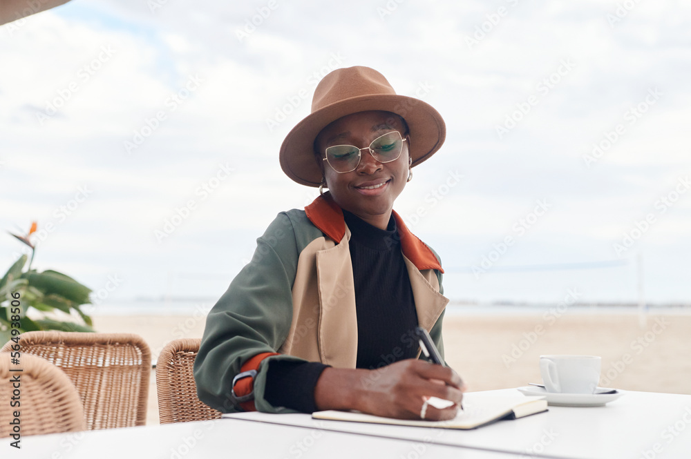 Smiling woman journaling at a seaside cafe Smiling woman journaling at a seaside cafe