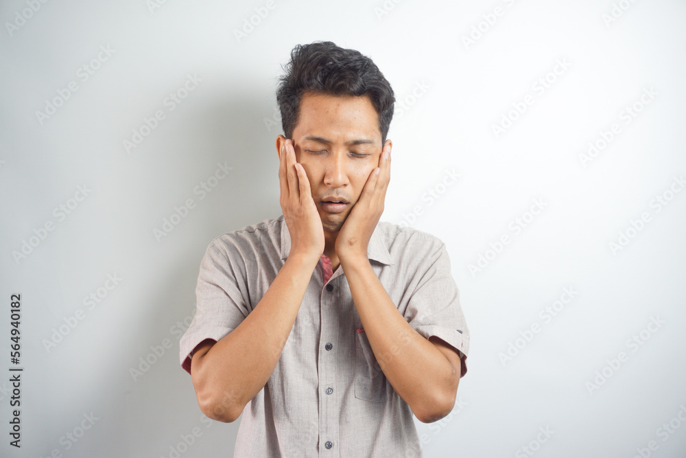 Tooth ache concept. Indoor shot of young male feeling pain, holding his cheek with hand, suffering from bad toothache, looking at camera with painful expression Tooth ache concept. Indoor shot of young male feeling pain, holding his cheek with hand, suffering from bad toothache, looking at camera with painful expression
